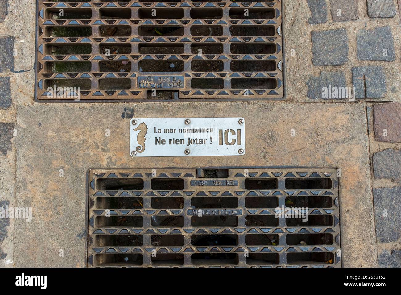 'La mer commence d'ici. Panneau « ne pas jeter les ordures » avec système de drainage à grille métallique sur route, Marseillan, Hérault, Occitanie, France, Europe Banque D'Images