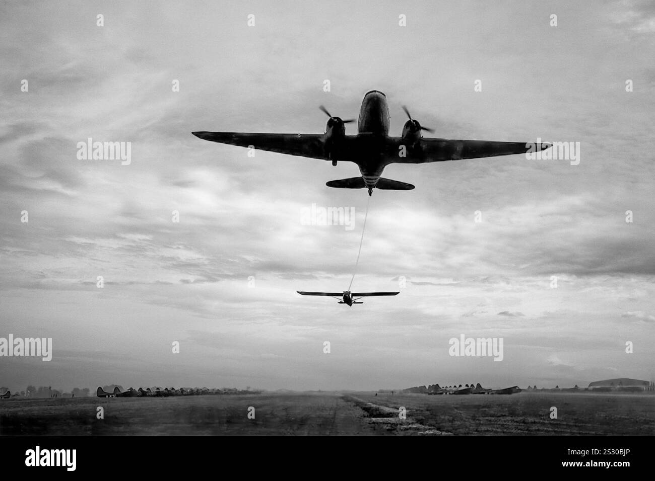 Un Douglas Dakota DC-3 remorquant un planeur du 101st Airborne pendant l'opération Market Garden. Le Dakota était un monoplan métallique à aile basse avec train d'atterrissage conventionnel, propulsé par deux moteurs à pistons radiaux, il était rapide, avec une bonne autonomie, fiable et pouvait fonctionner à partir de pistes courtes. Pendant la seconde Guerre mondiale, plus de 10 000 versions militaires américaines du DC-3 ont été construites, les forces armées de nombreux pays utilisant le DC-3 et ses variantes militaires pour le transport de troupes, de marchandises et de blessés. Banque D'Images