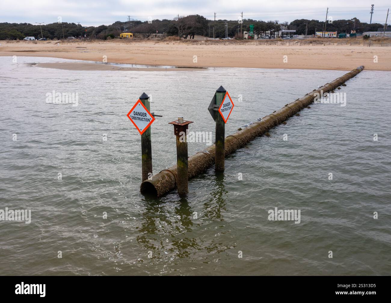 Vue aérienne du tuyau d'égout pluvial rouillé à la plage avec un panneau indiquant danger obstruction Banque D'Images