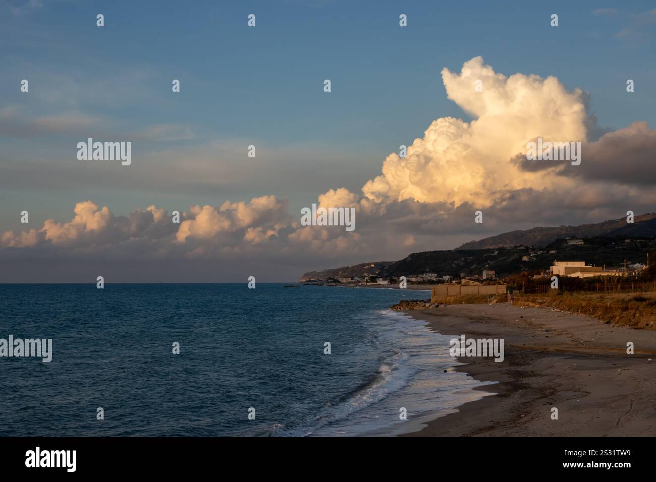Soirée à la plage de sable au moment du coucher du soleil. Calme mer Tyrrhénienne (Méditerranée). Nuage lumineux enligé par la lumière du soleil. Torregrotta, Sicile, I. Banque D'Images