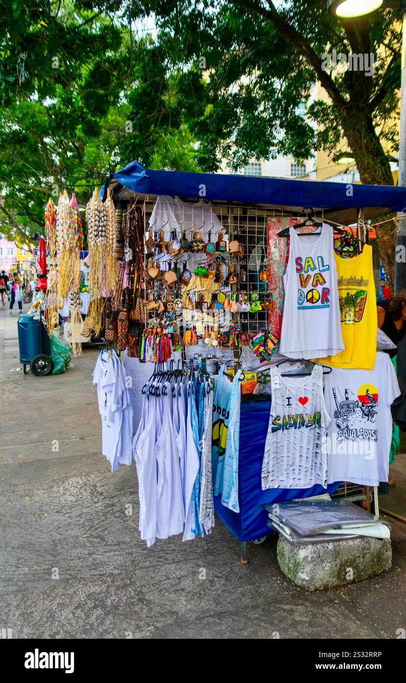 Stand souvenir dans Pelourinho 'Praça da Sé', place avec de l'artisanat et des T-shirts à l'ombre des arbres tropicaux. La culture de rue de Salvador est exposée. Banque D'Images