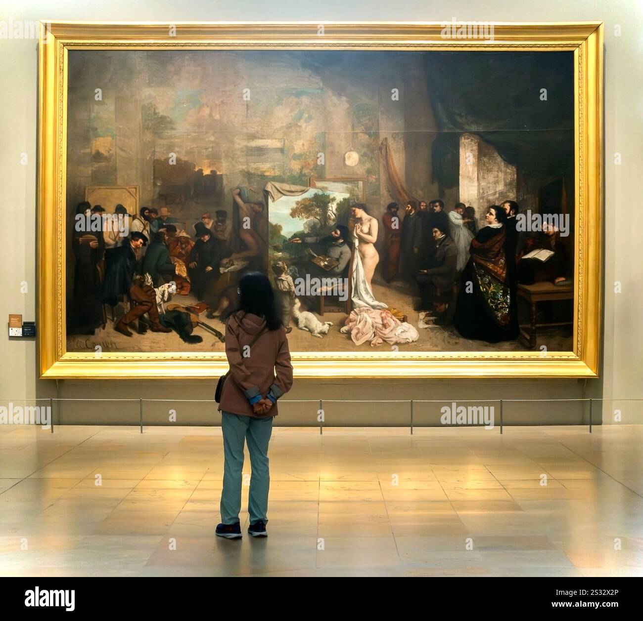 Une femme se tient devant la peinture à l'huile L'Atelier du peintre de Gustave Courbert au Musée d'Orsay, Paris, France Banque D'Images