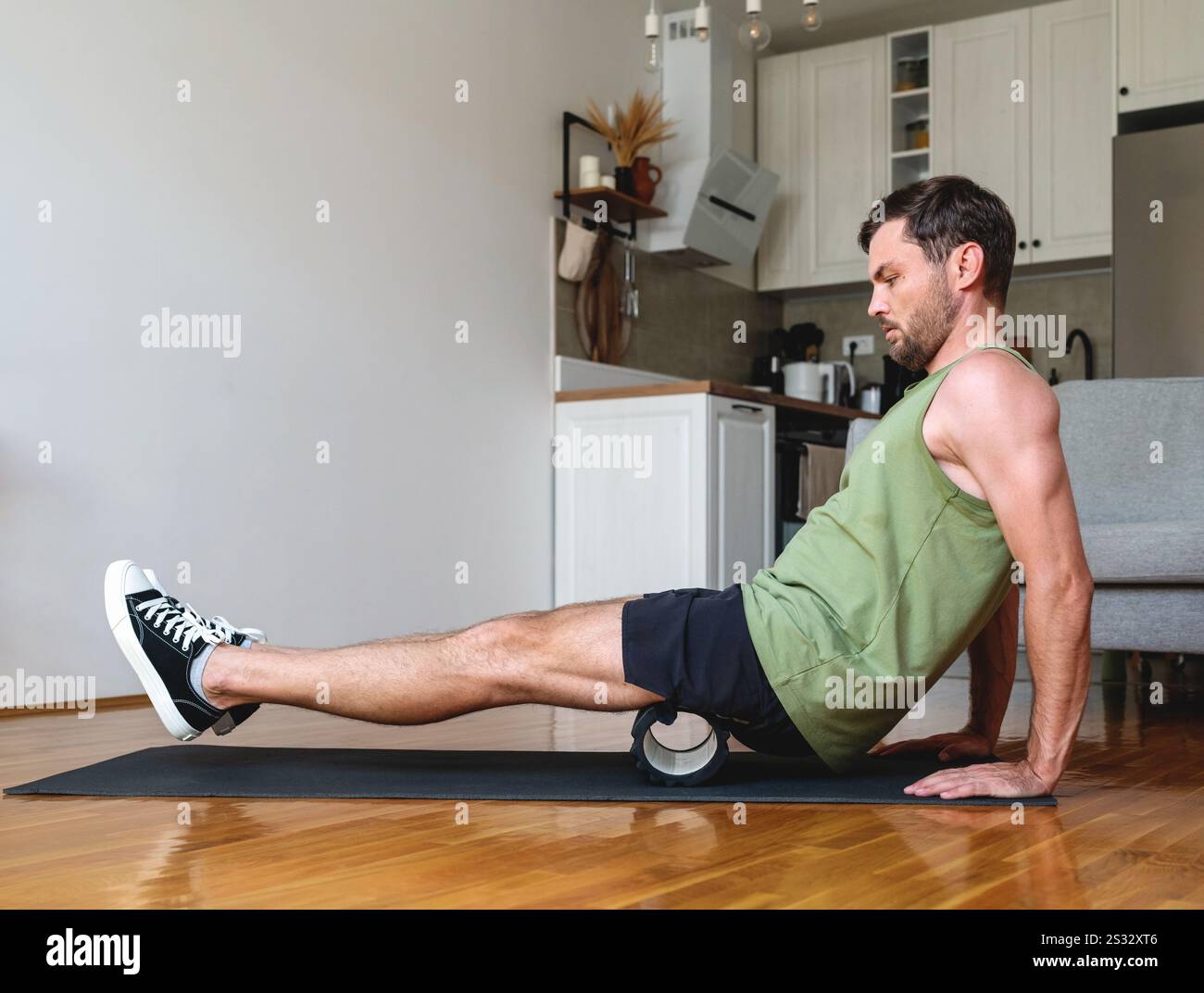Homme caucasien faisant de l'exercice sportif à la maison en utilisant le rouleau de mousse. Banque D'Images