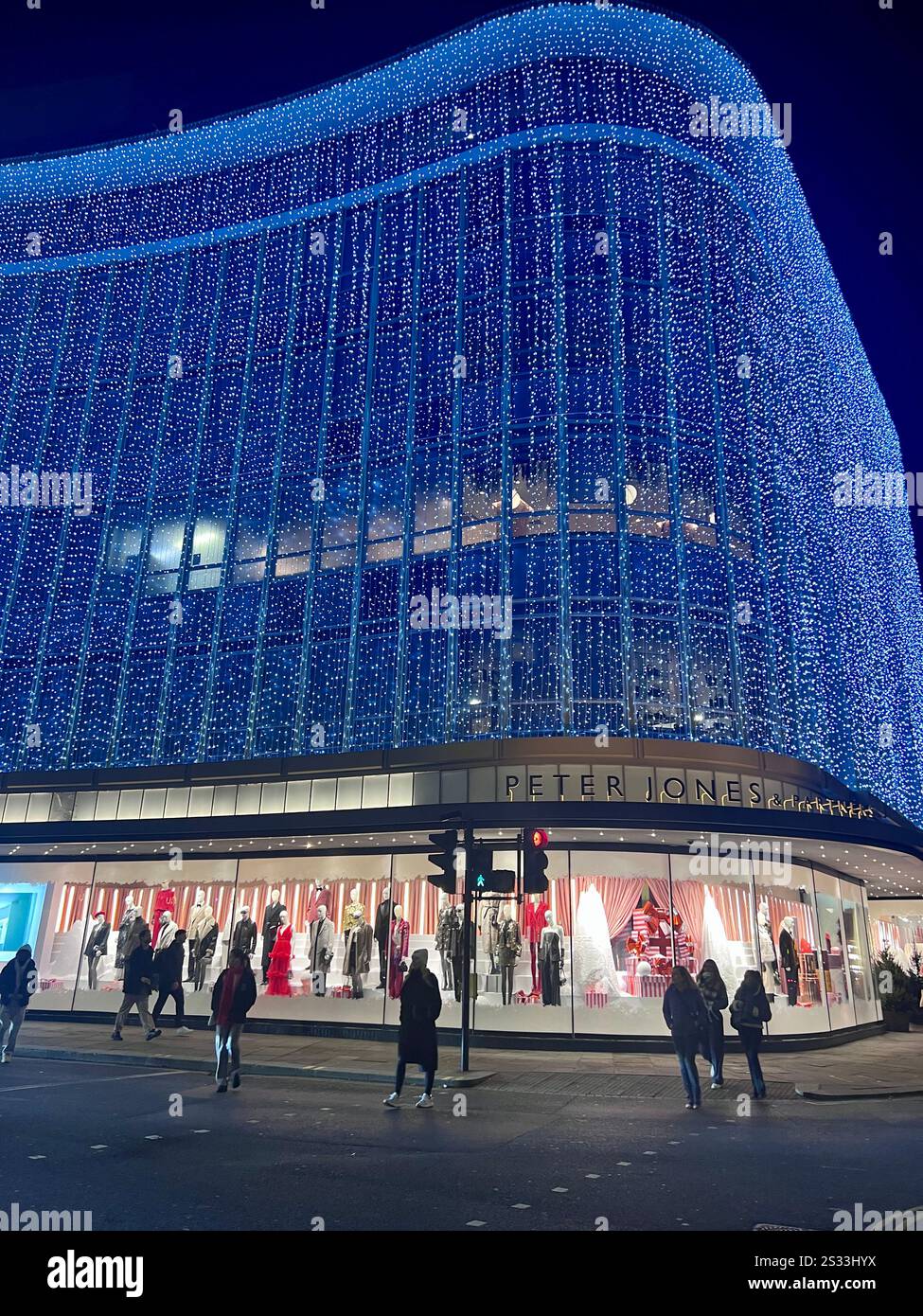 Façade du grand magasin Peter Jones (un magasin John Lewis) la nuit décorée avec des lumières de Noël à l'extérieur. Avec des gens marchant dehors. Banque D'Images