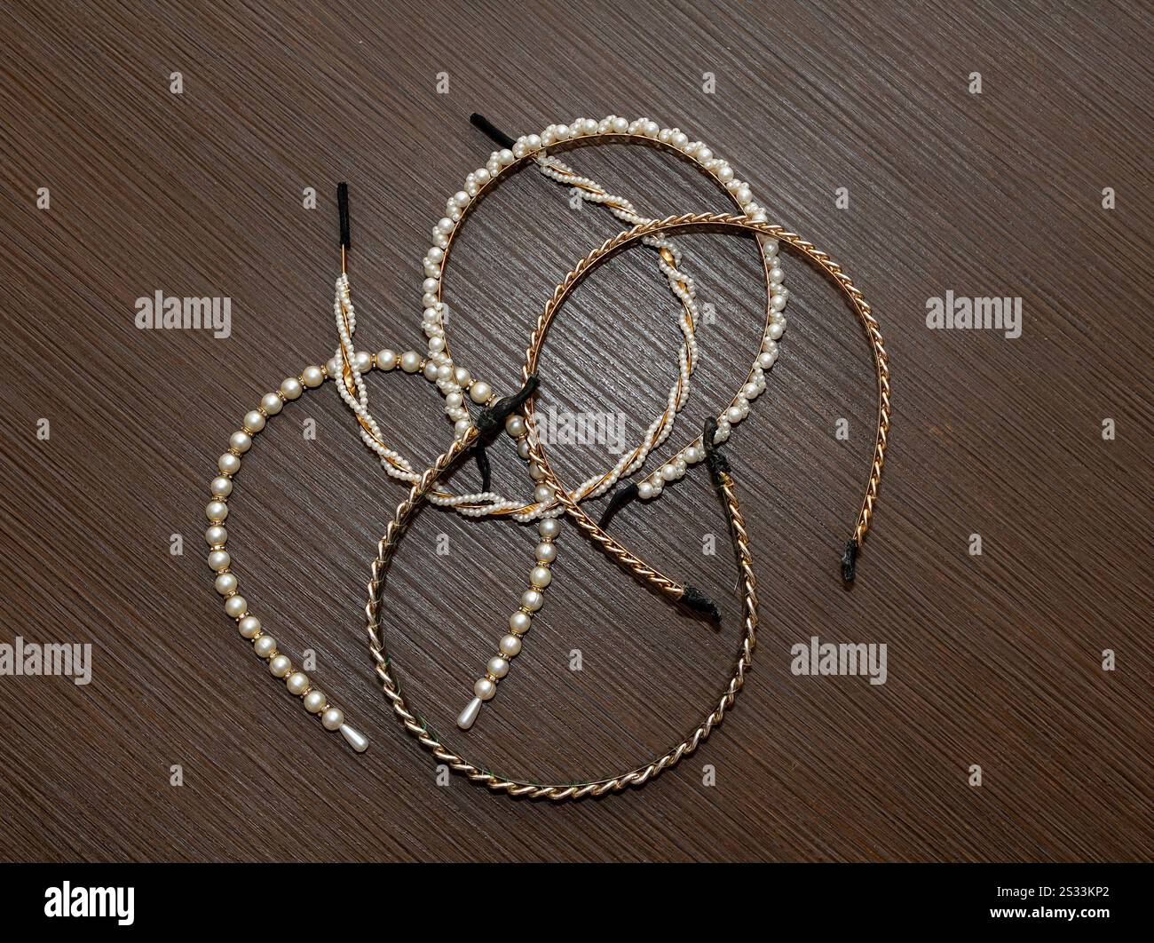 Bandes de cheveux en métal doré pile avec perles et pierres étincelantes décor sur la table en bois Banque D'Images