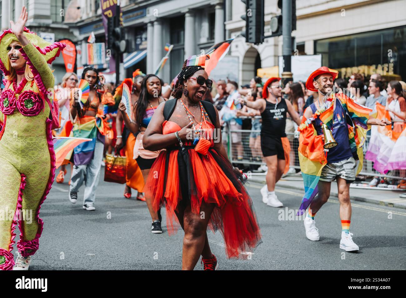 Foule diversifiée célébrant Pride Parade avec des tenues colorées et des drapeaux arc-en-ciel Banque D'Images