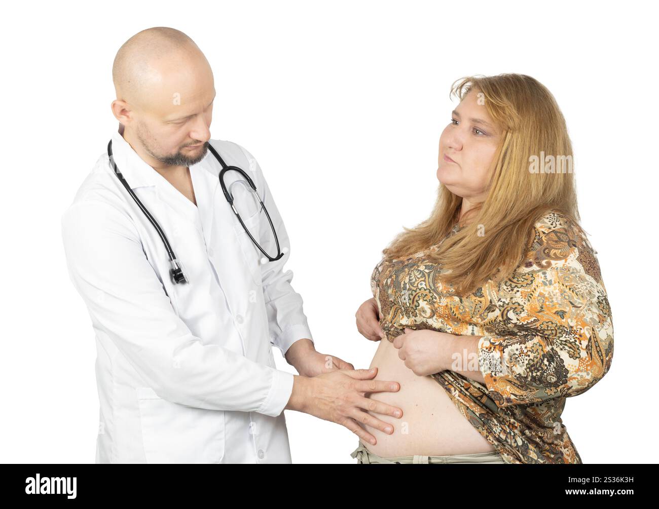 Un médecin de sexe masculin en manteau blanc avec un stéthoscope examine l'abdomen d'une patiente. Banque D'Images