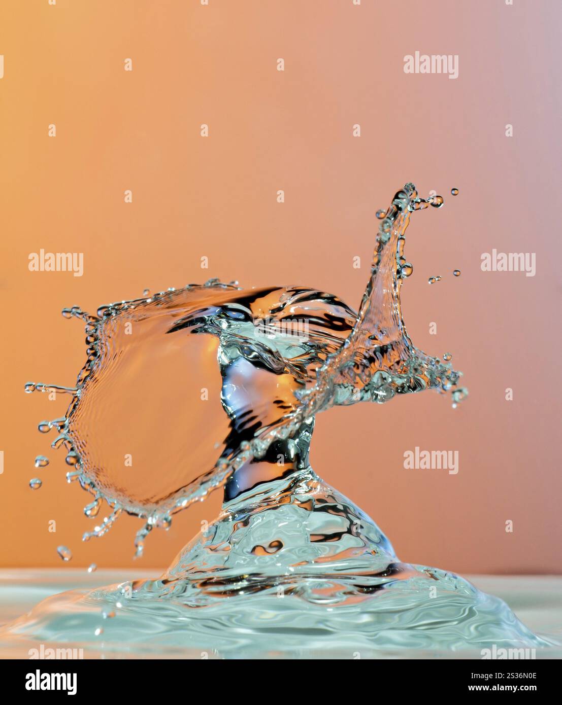 Gouttelettes d'eau dansantes photographie à grande vitesse sur fond orange Banque D'Images