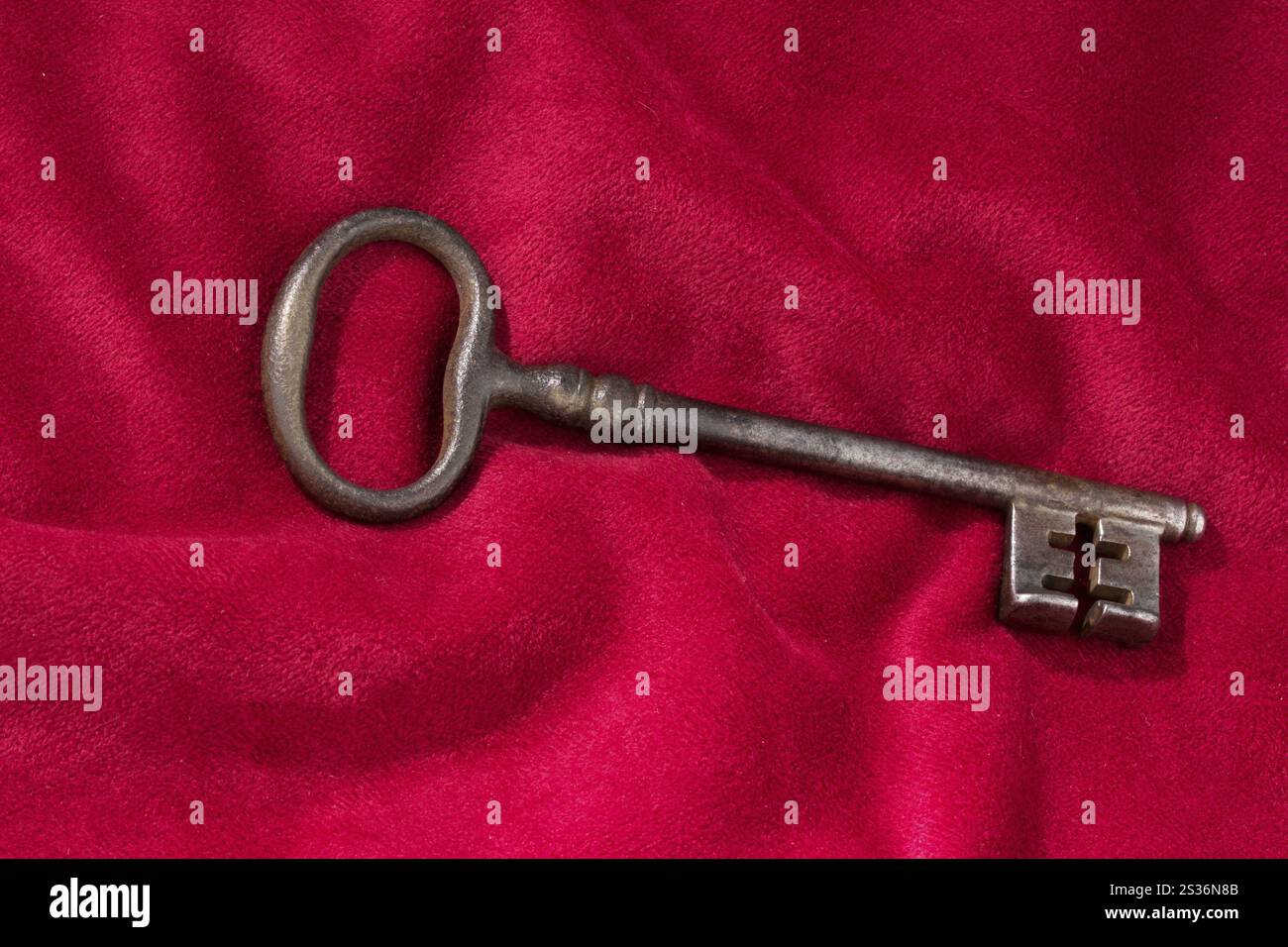 Une clé repose sur un coussin en velours rouge. Photo symbolique pour la remise des clés à une entreprise. Autriche Banque D'Images Une clé repose sur un coussin en velours rouge. Photo symbolique pour la remise des clés à une entreprise. Autriche Banque D'Images