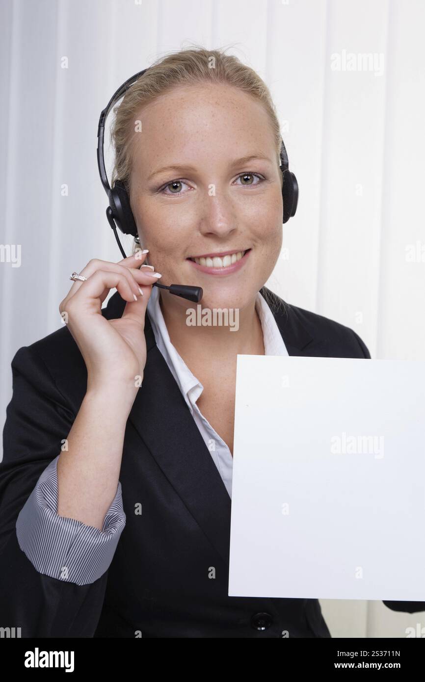 Une jeune femme amicale avec un casque dans le service à la clientèle est au téléphone avec un client. Employé sympathique de la hotline. Autriche Banque D'Images