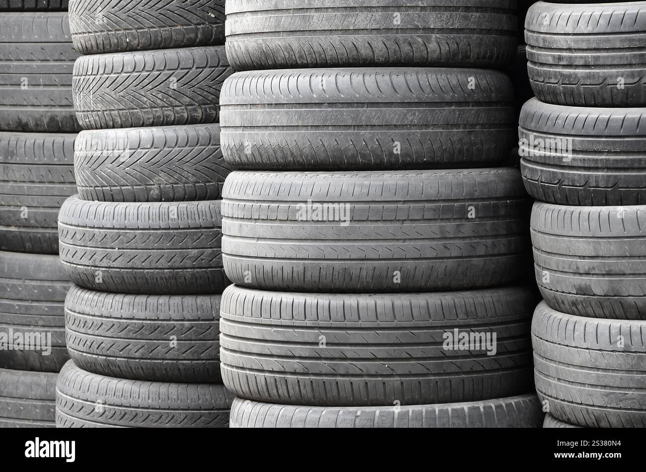Vieux pneus usagés empilés avec des piles élevées dans le garage secondaire de magasin de pièces de voiture de près. Vieux pneus usagés empilés avec des piles élevées dans des pièces de voiture secondaires Banque D'Images