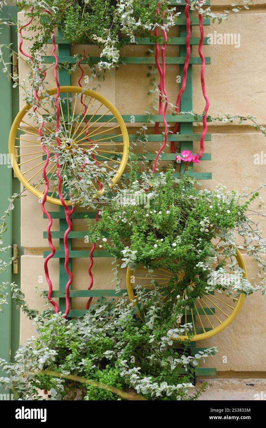 Décoration objet d'art urbain de roues de vélo et fleurs élégantes colorées sur le mur. Décoration objet d'art urbain de roues de vélo et de fleurs sur Banque D'Images