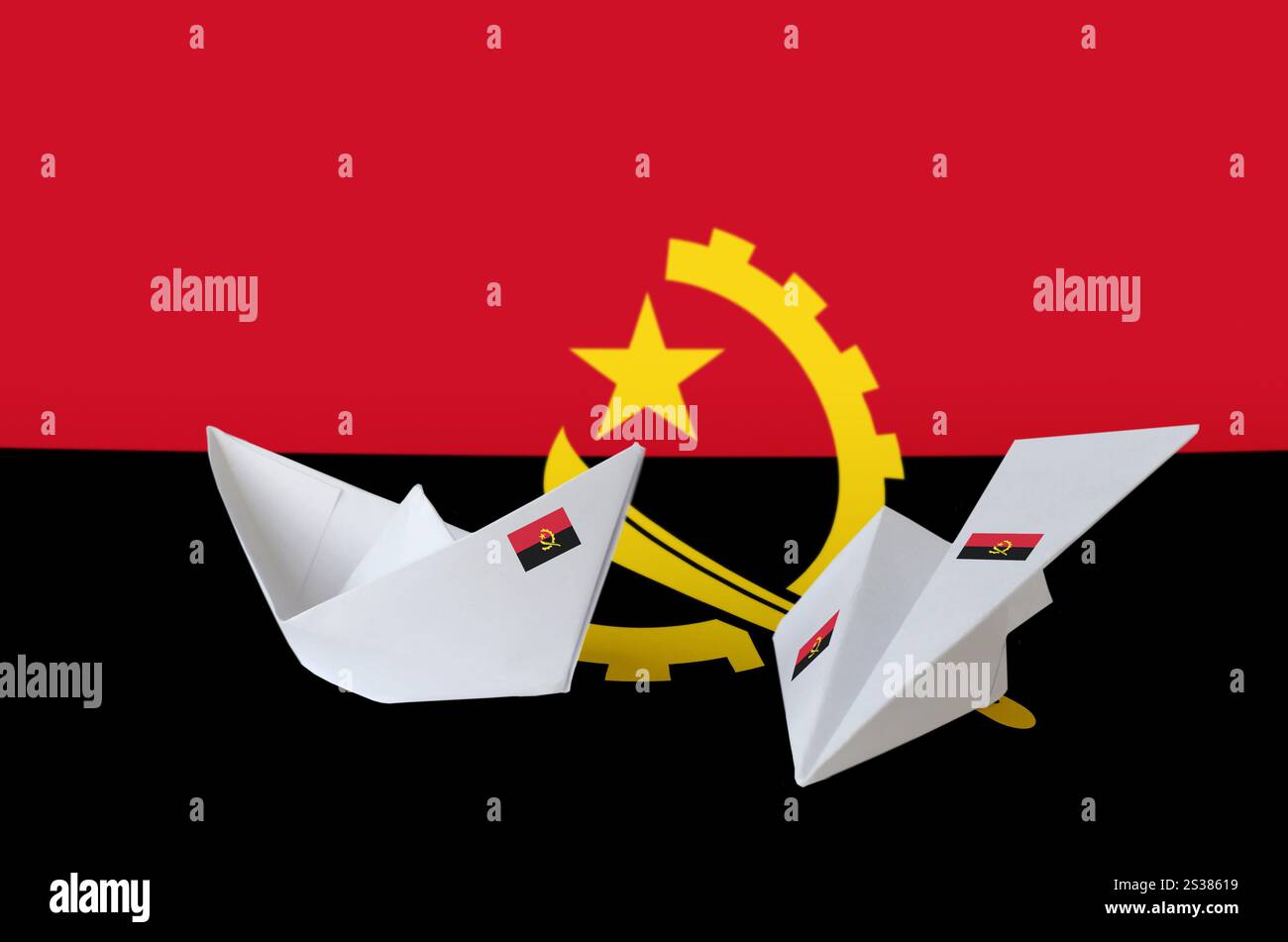 Drapeau angolais représenté sur un avion et un bateau en origami en papier. Concept d'arts orientaux faits à la main. Drapeau angolais représenté sur un avion et un bateau en origami en papier. Banque D'Images