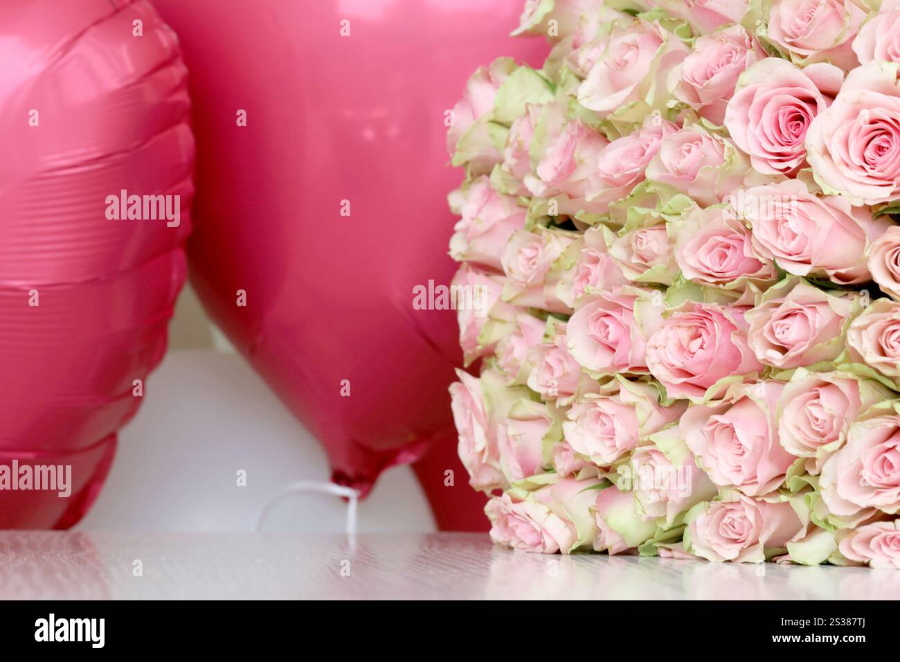 Bouquet de roses colorées et de ballons rouges en forme de coeur en gros plan. Fleurs roses plein cadre. Bouquet de roses colorées et ballons rouges en forme de Banque D'Images