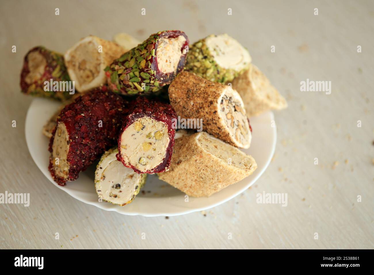 De nombreux rouleaux de plaisir turc avec différentes saveurs et garnitures dans une assiette blanche sur la table. Coupes de bonbons Turk Lokumu. Beaucoup de petits pains de plaisir turc Banque D'Images