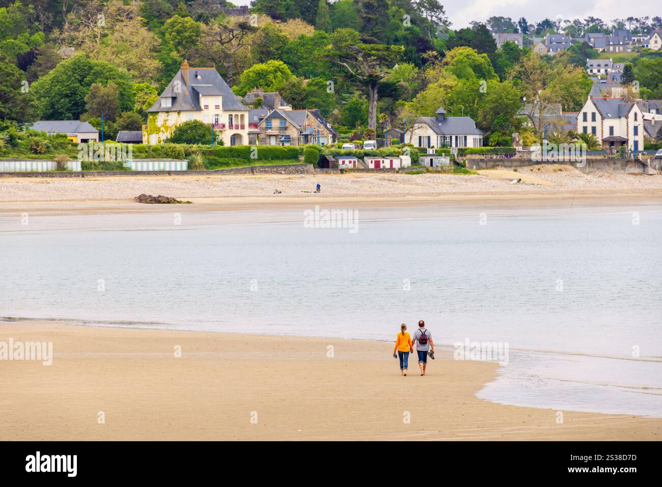 Village côtier sur la côte française en Bretagne avec un couple marchant sur la plage Banque D'Images