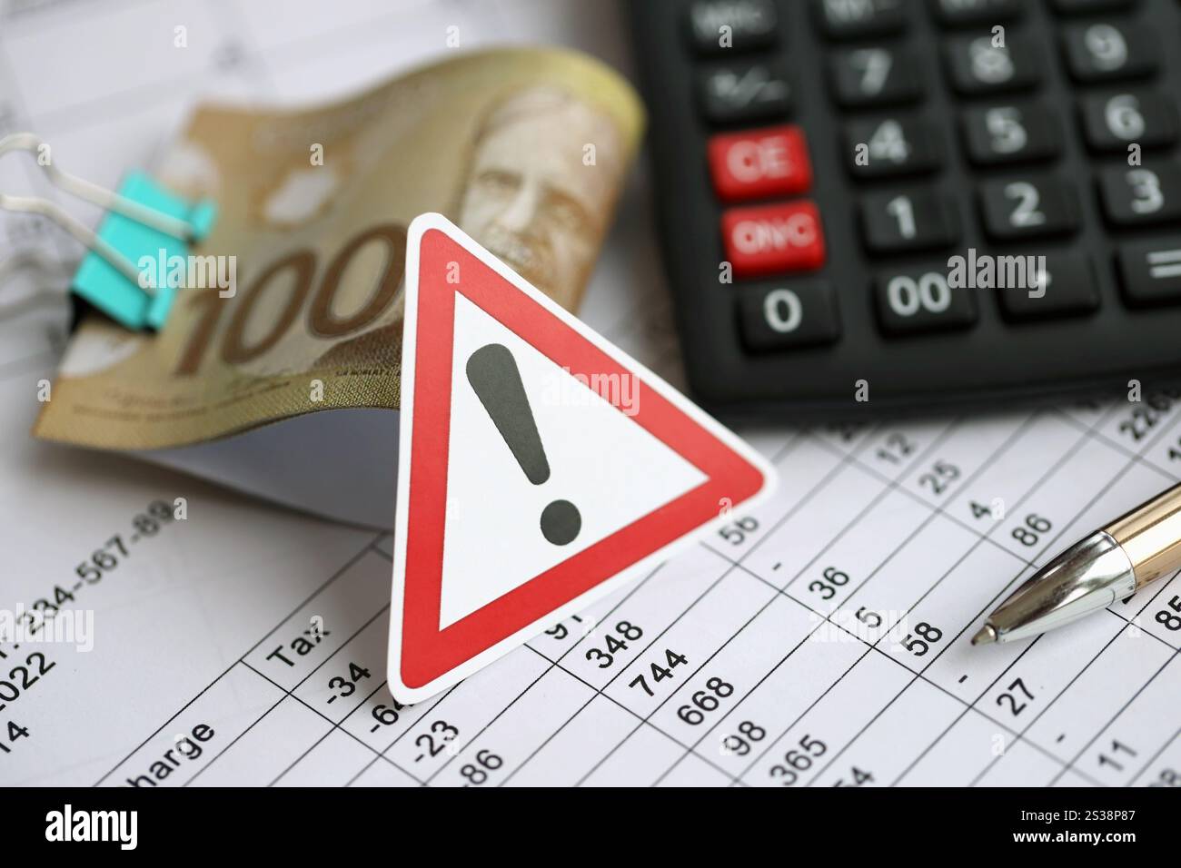 Signe d'attention et les résultats de calcul dans les horaires se trouvent sur la table avec des billets de monnaie canadiens, une calculatrice et un stylo en gros plan. Fiscalité et annuelle Banque D'Images