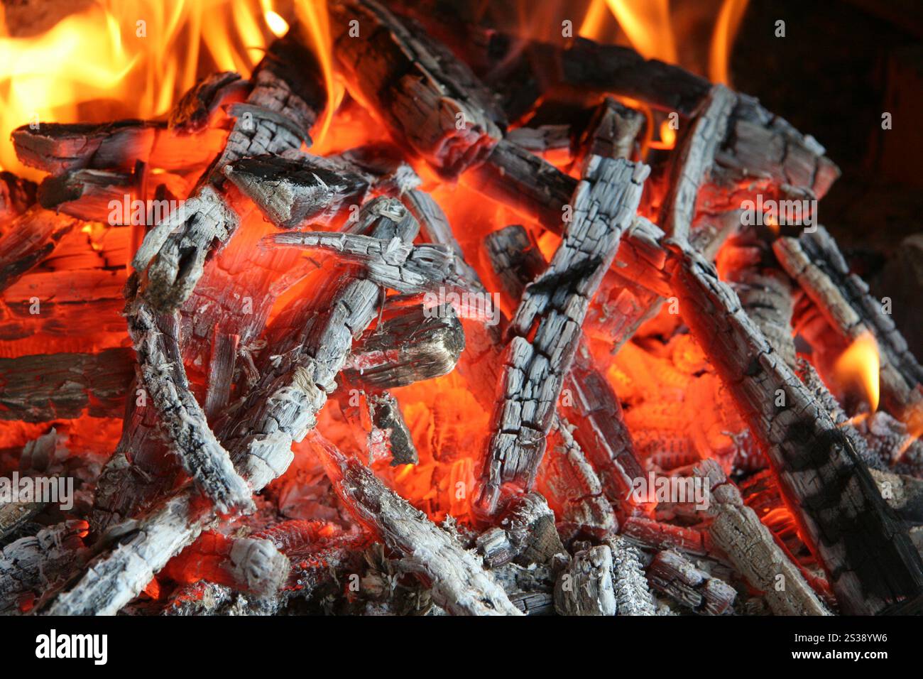 Gros plan de bois en feu avec des braises vibrantes et des flammes vives. Braises incandescentes et flammes dans le feu de bois Banque D'Images