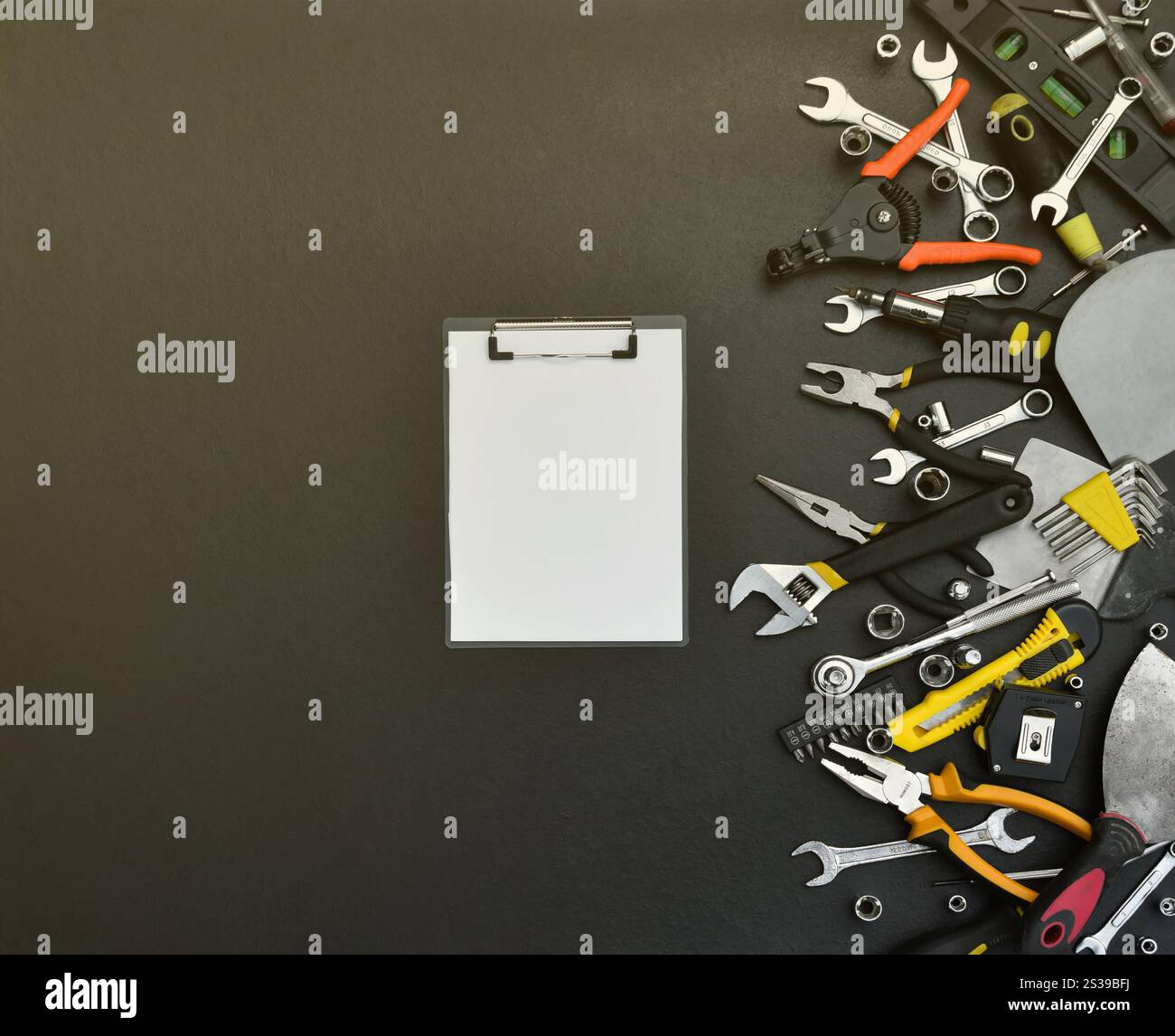 Kit d'outils bricoleur sur table en bois noir. De nombreuses clés et tournevis, pilers et autres outils pour tout type de travaux de réparation ou de construction. Banque D'Images