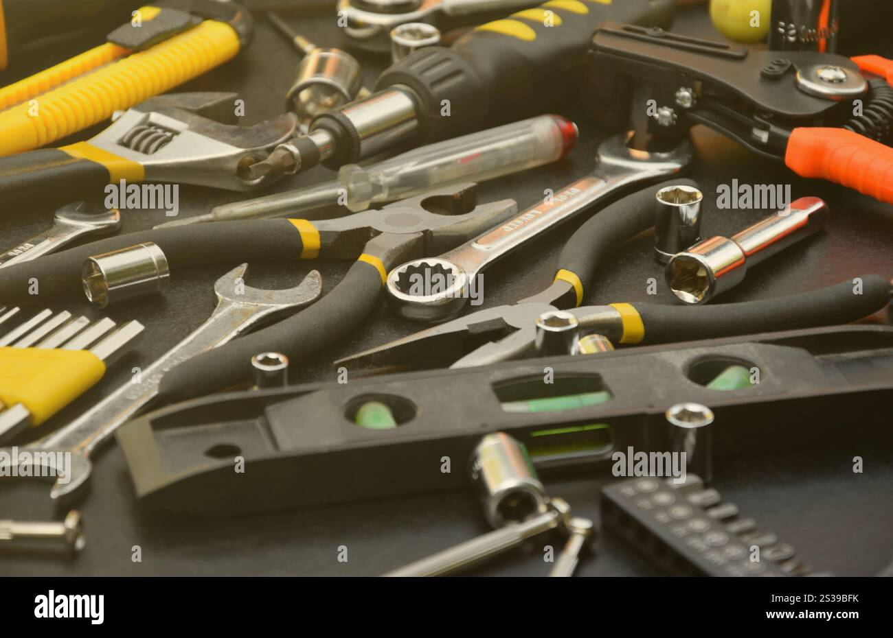 Kit d'outils bricoleur sur table en bois noir. De nombreuses clés et tournevis, pilers et autres outils pour tout type de travaux de réparation ou de construction. Banque D'Images