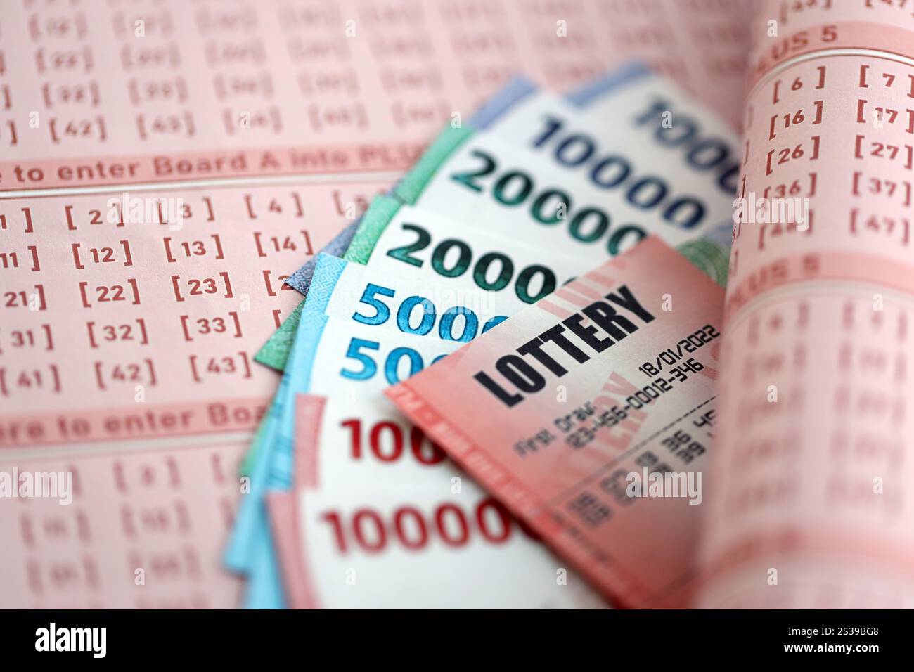 Billet de loterie rouge se trouve sur des feuilles de jeu roses avec des factures d'argent rupiah indonésiennes. Concept de jeu de loterie ou dépendance au jeu en indonésie. Rouge Banque D'Images