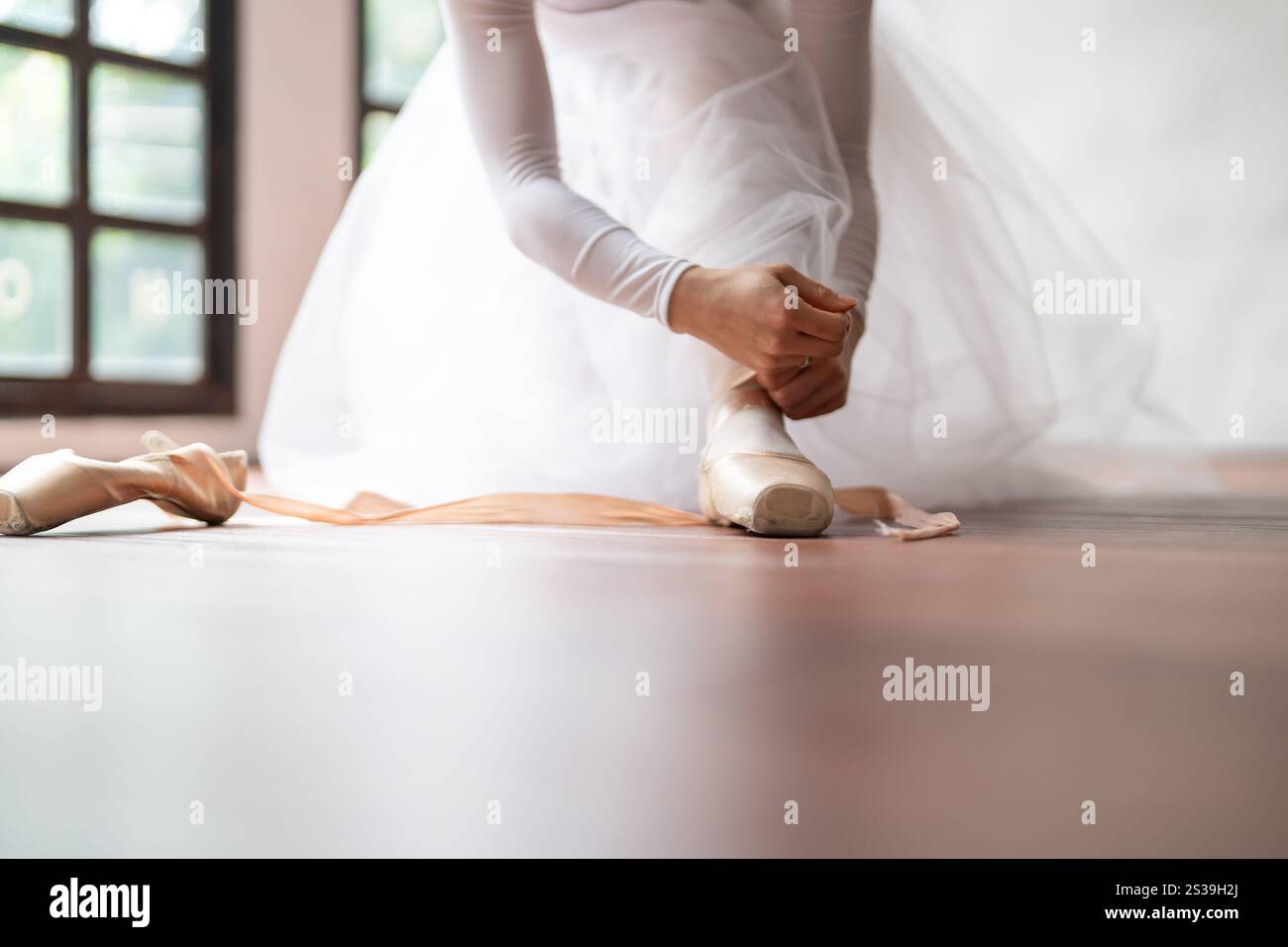 Ballerine en chaussures de ballet. Fille asiatique nouant des rubans de chaussures d'orteil. danseuse de ballet préparant et portant des chaussures de ballet dans le studio de danse prépare pour un Banque D'Images