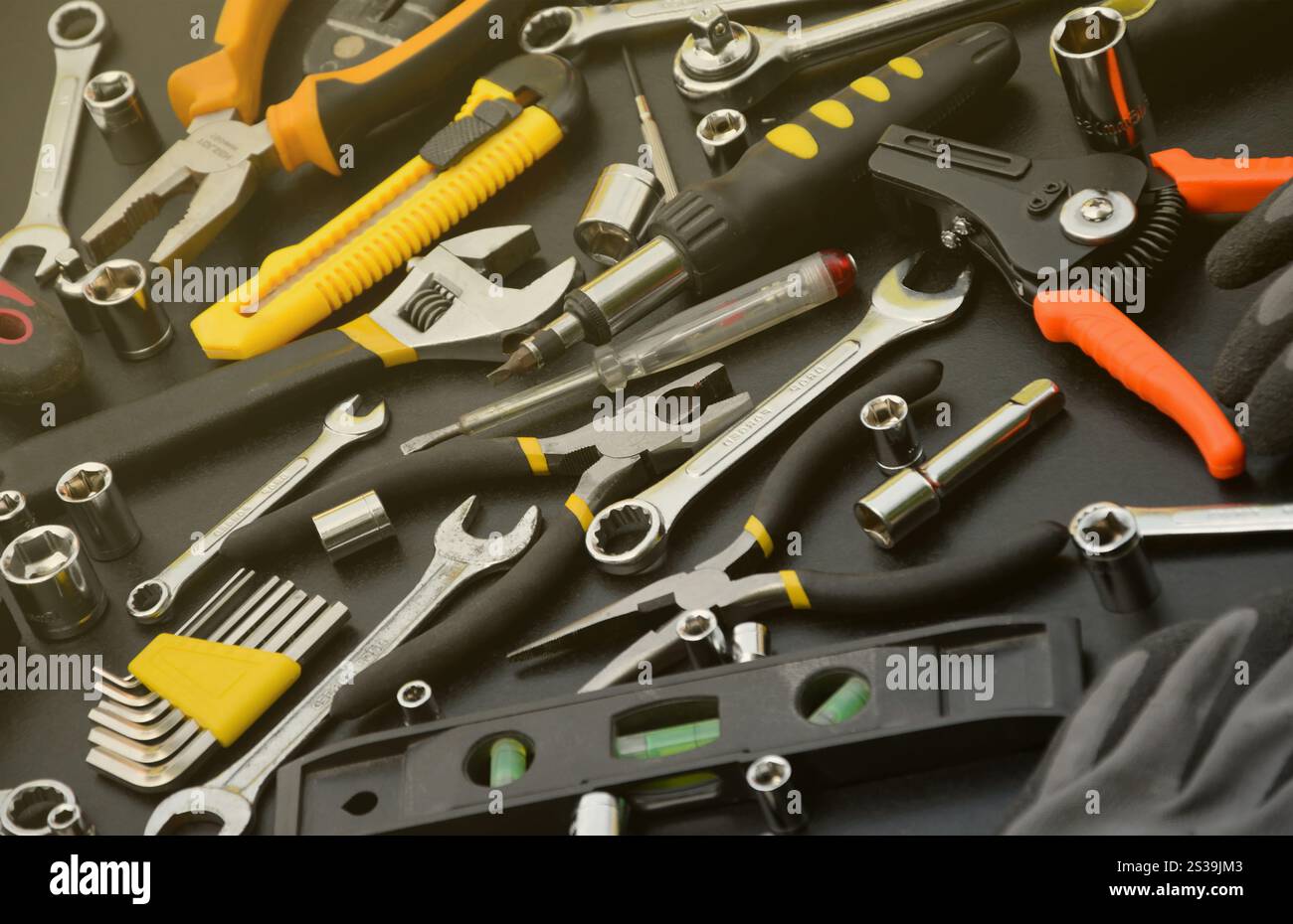 Kit d'outils bricoleur sur table en bois noir. De nombreuses clés et tournevis, pilers et autres outils pour tout type de travaux de réparation ou de construction. Banque D'Images