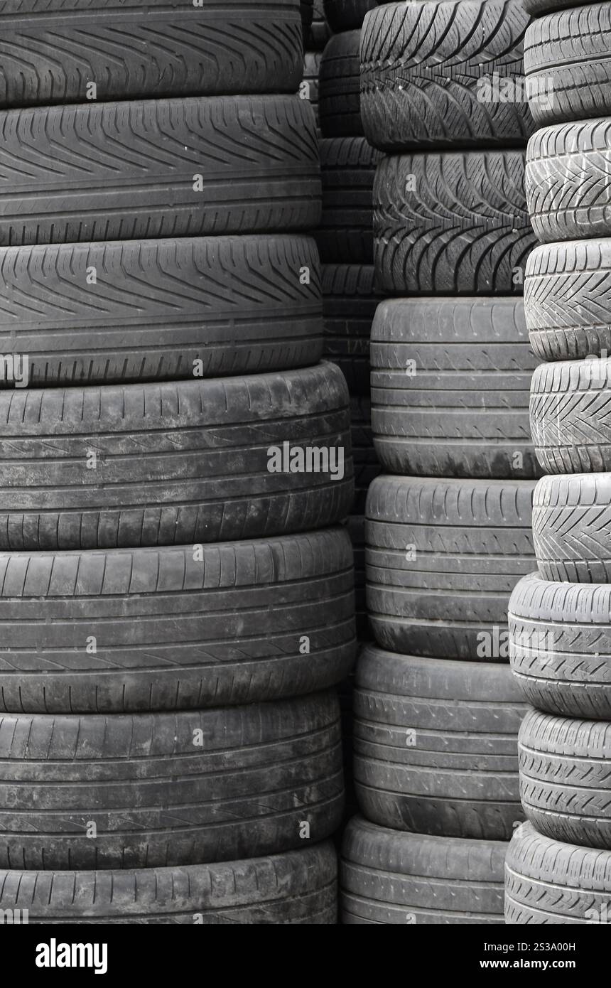 Vieux pneus usagés empilés avec des piles élevées dans le garage secondaire de magasin de pièces de voiture de près. Vieux pneus usagés empilés avec des piles élevées dans des pièces de voiture secondaires Banque D'Images