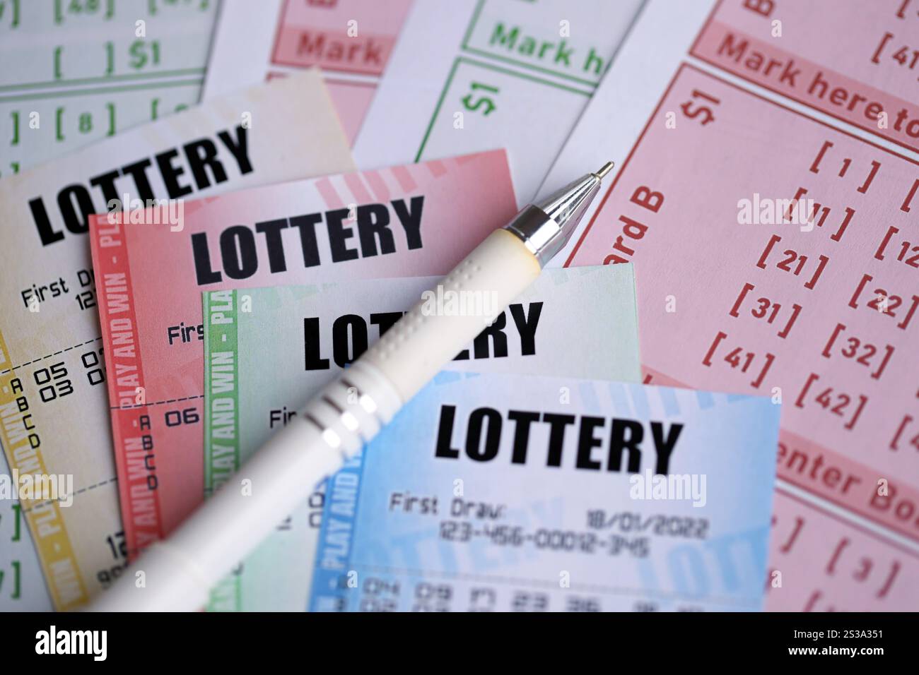 Billets de loterie de différentes couleurs et stylo sur des billets vierges avec des numéros pour jouer à la loterie en gros plan. Billets de loterie de différentes couleurs et stylo dessus Banque D'Images