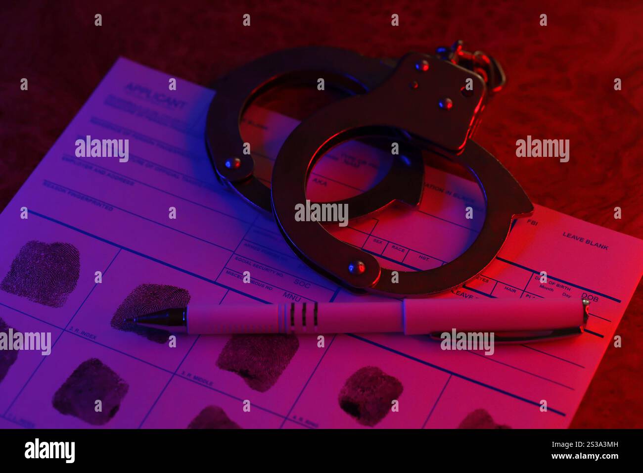 Demandeur ou empreintes digitales carte avec menottes de police sur la table dans la chambre sombre de près. Carte du demandeur ou empreintes digitales avec menottes de police sur la table Banque D'Images