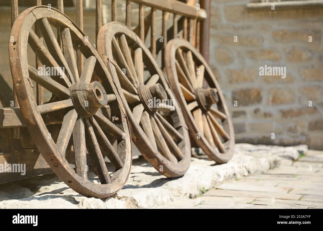 Trois vieilles roues en bois pour charrettes à chevaux appuyées contre un mur de bois en perspective. Trois vieilles roues en bois pour charrettes à chevaux appuyées contre un Banque D'Images