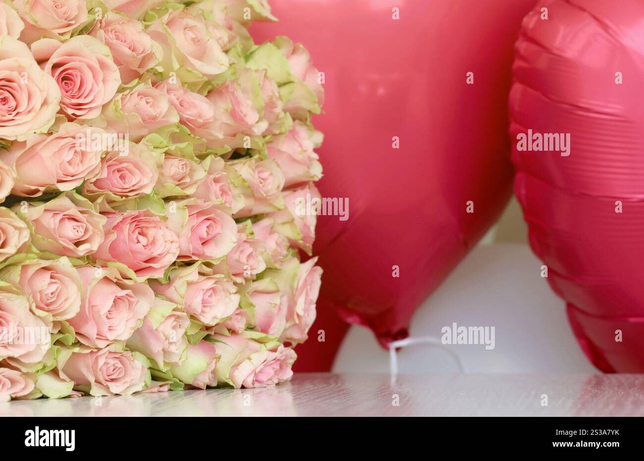 Bouquet de roses colorées et de ballons rouges en forme de coeur en gros plan. Fleurs roses plein cadre. Bouquet de roses colorées et ballons rouges en forme de Banque D'Images