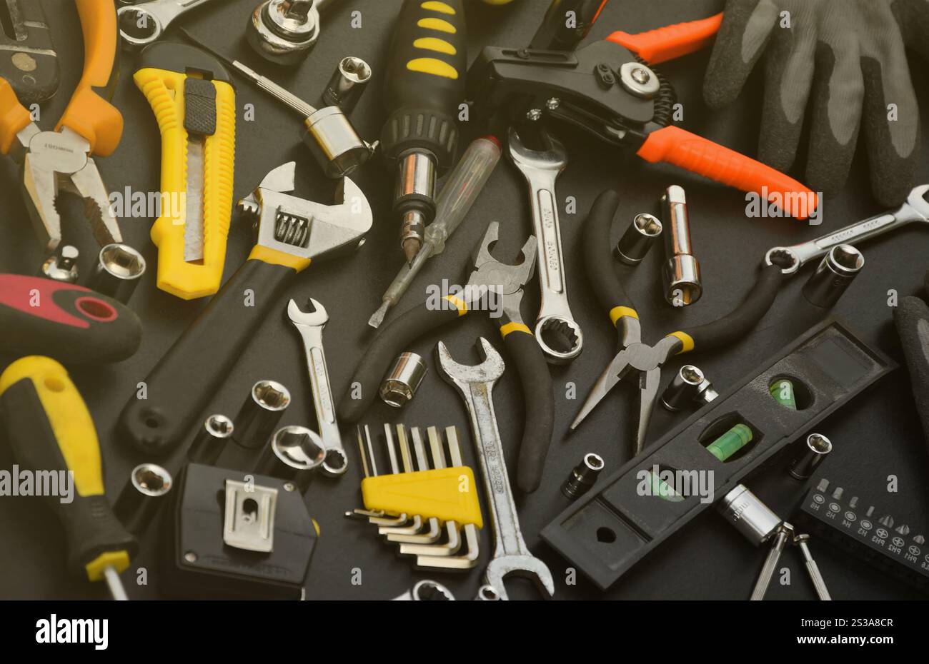 Kit d'outils bricoleur sur table en bois noir. De nombreuses clés et tournevis, pilers et autres outils pour tout type de travaux de réparation ou de construction. Banque D'Images