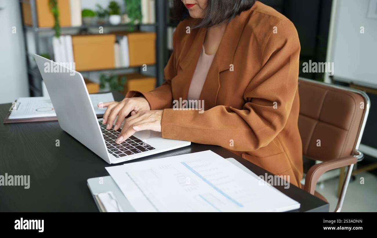 Entreprise mature femme entrepreneur asiatique dans le bureau à l'aide d'un ordinateur portable. femme d'affaires des années 60 avec la technologie femme senior asiatique. Banque D'Images