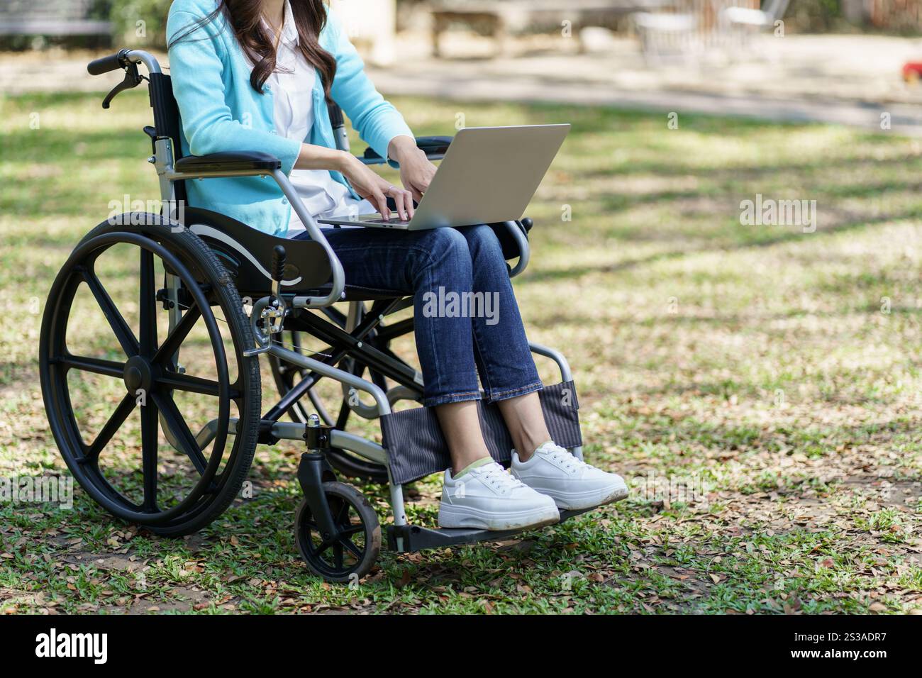 Jeune femme asiatique en fauteuil roulant travaillant avec un ordinateur portable Banque D'Images