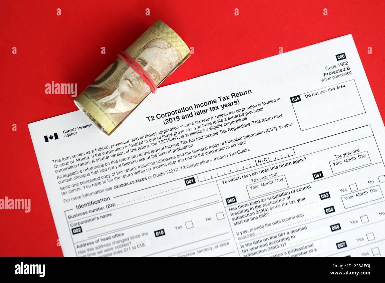 Formulaire d'impôt T2 canadien la déclaration de revenus des sociétés est sur la table avec les factures de monnaie canadiennes en gros plan. Fiscalité et documents comptables annuels dans Banque D'Images