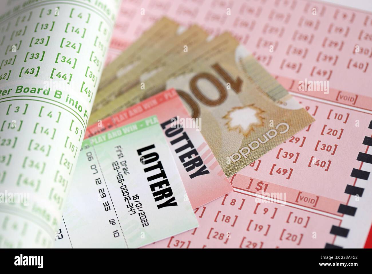 Billets de loterie se trouve avec des dollars canadiens sur des feuilles de jeu avec des numéros pour marquer pour jouer à la loterie. Concept de jeu de loterie ou jeu Banque D'Images