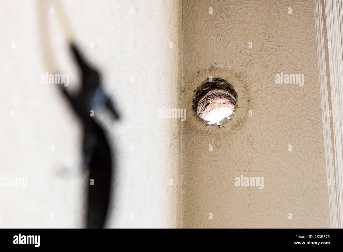 trou dans le mur du salon dans l'appartement et des fils électriques enveloppés avec du ruban électrique hors foyer au premier plan pendant le climatiseur Banque D'Images