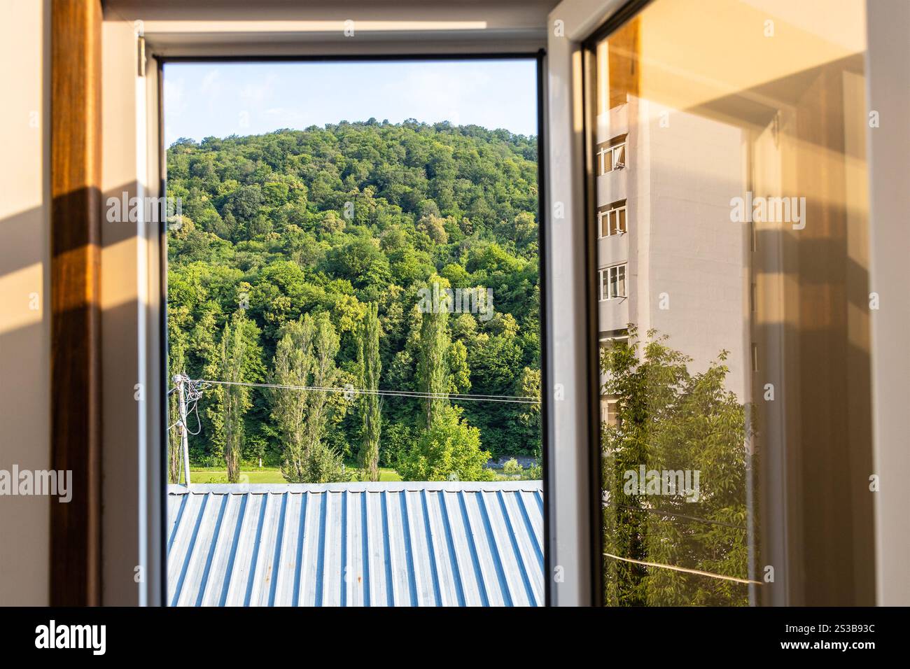 Vue sur le toit et la montagne verte à travers la fenêtre ouverte le jour ensoleillé d'été dans la ville de Dilijan, Arménie Banque D'Images