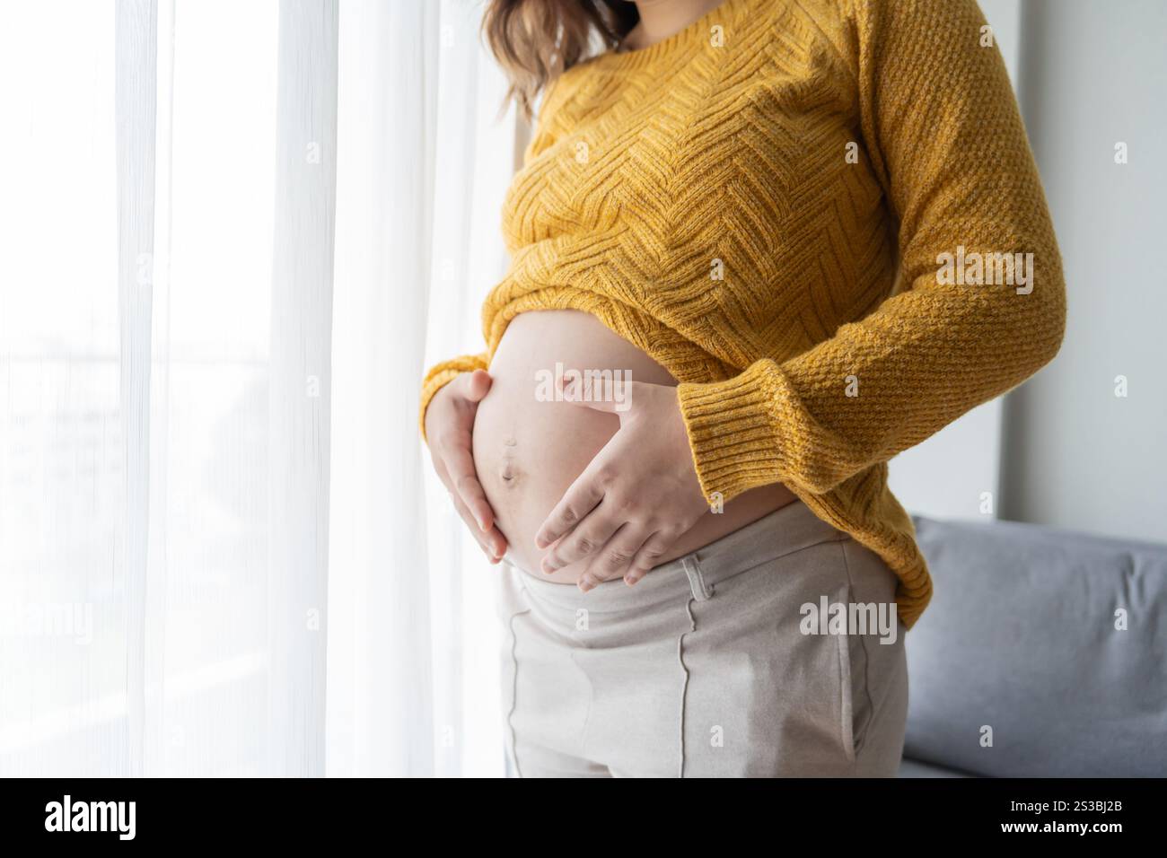 Femme enceinte tient les mains sur le ventre touchant son bébé se souciant de sa santé belle femme enceinte heureuse photo d'humeur tendre de la grossesse. Banque D'Images