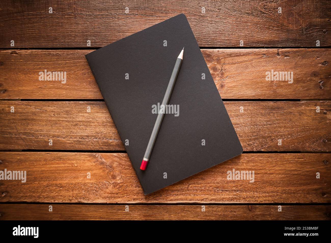 Cahier fermé et crayon sur une planche de bois vintage rustique. Cahier fermé et crayon sur une planche de bois rustique Banque D'Images
