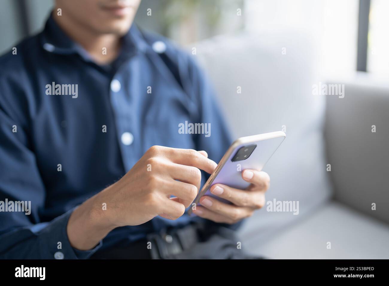 Détendu jeune homme asiatique à l'aide d'un téléphone intelligent passant du temps à vérifier les nouvelles médias sociaux. Banque D'Images