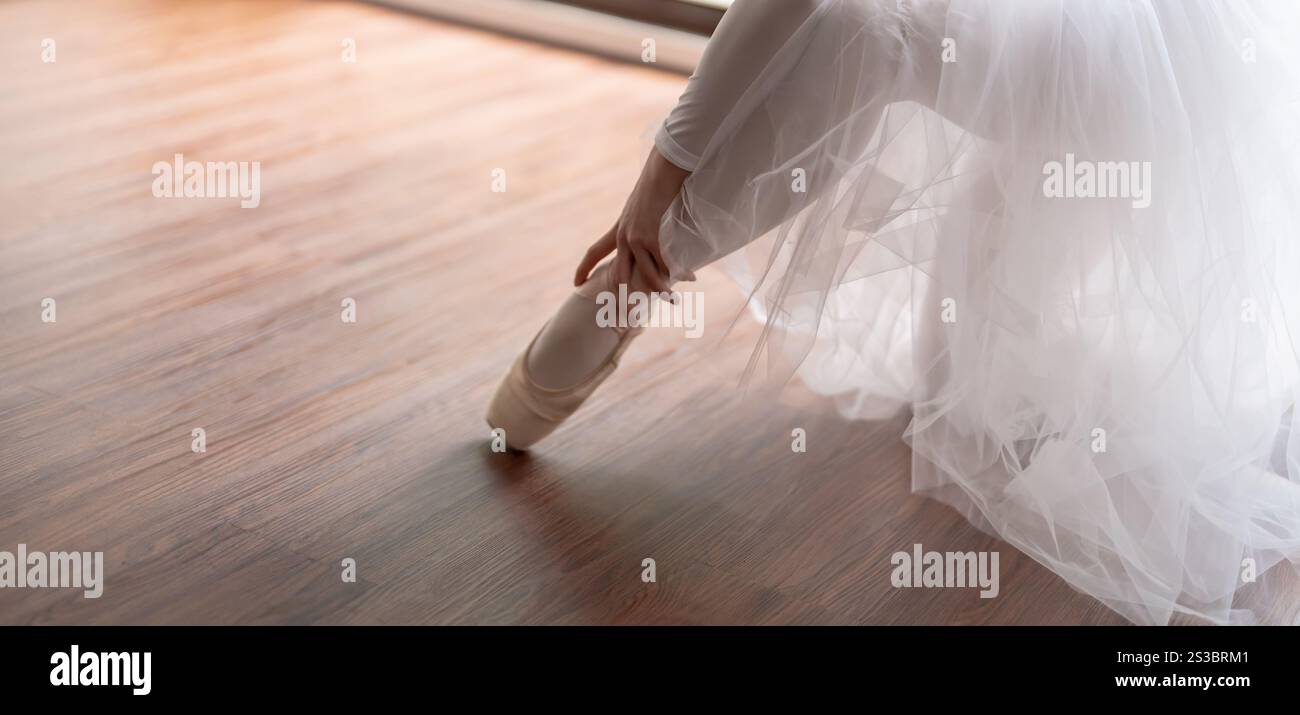 Ballerine en chaussures de ballet. Fille asiatique nouant des rubans de chaussures d'orteil. danseuse de ballet préparant et portant des chaussures de ballet dans le studio de danse prépare pour un Banque D'Images