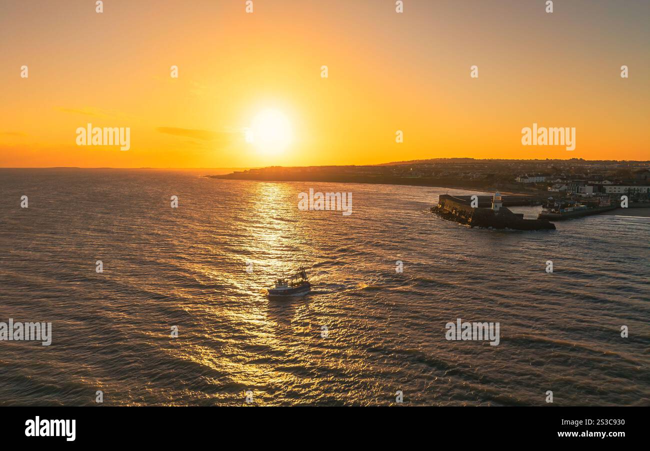Chalutier sortant du port de Balbriggan au lever du soleil Banque D'Images