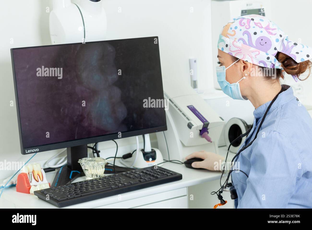 Dentiste travaillant à un ordinateur, analysant des images de radiographie dans une clinique dentaire de pointe, assurant des soins et un diagnostic optimaux aux patients Banque D'Images