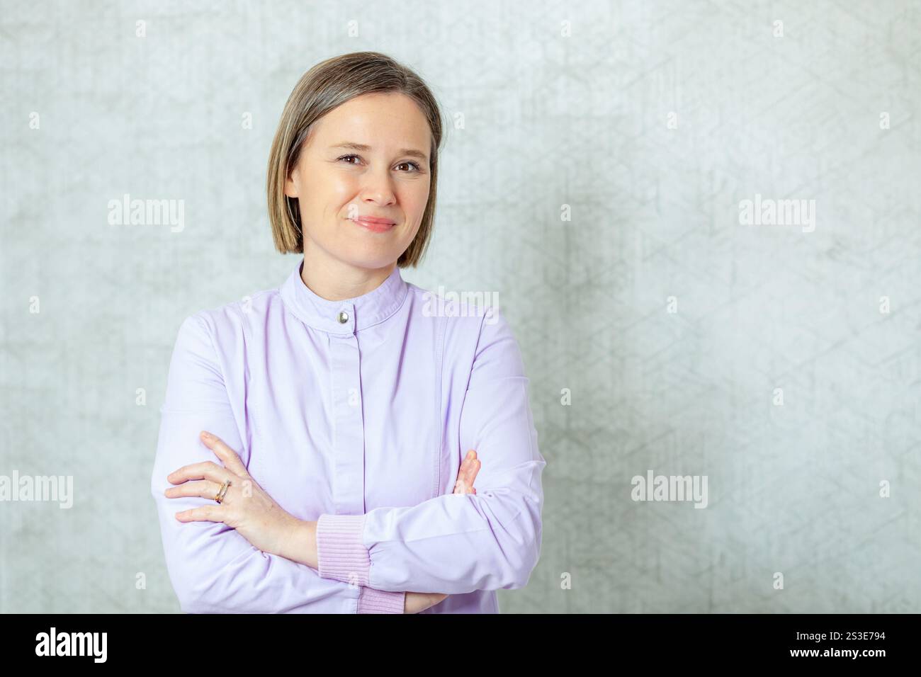 Portrait d’une dentiste souriante les bras croisés, mettant en valeur le professionnalisme et l’expertise dans un cadre de clinique dentaire Banque D'Images