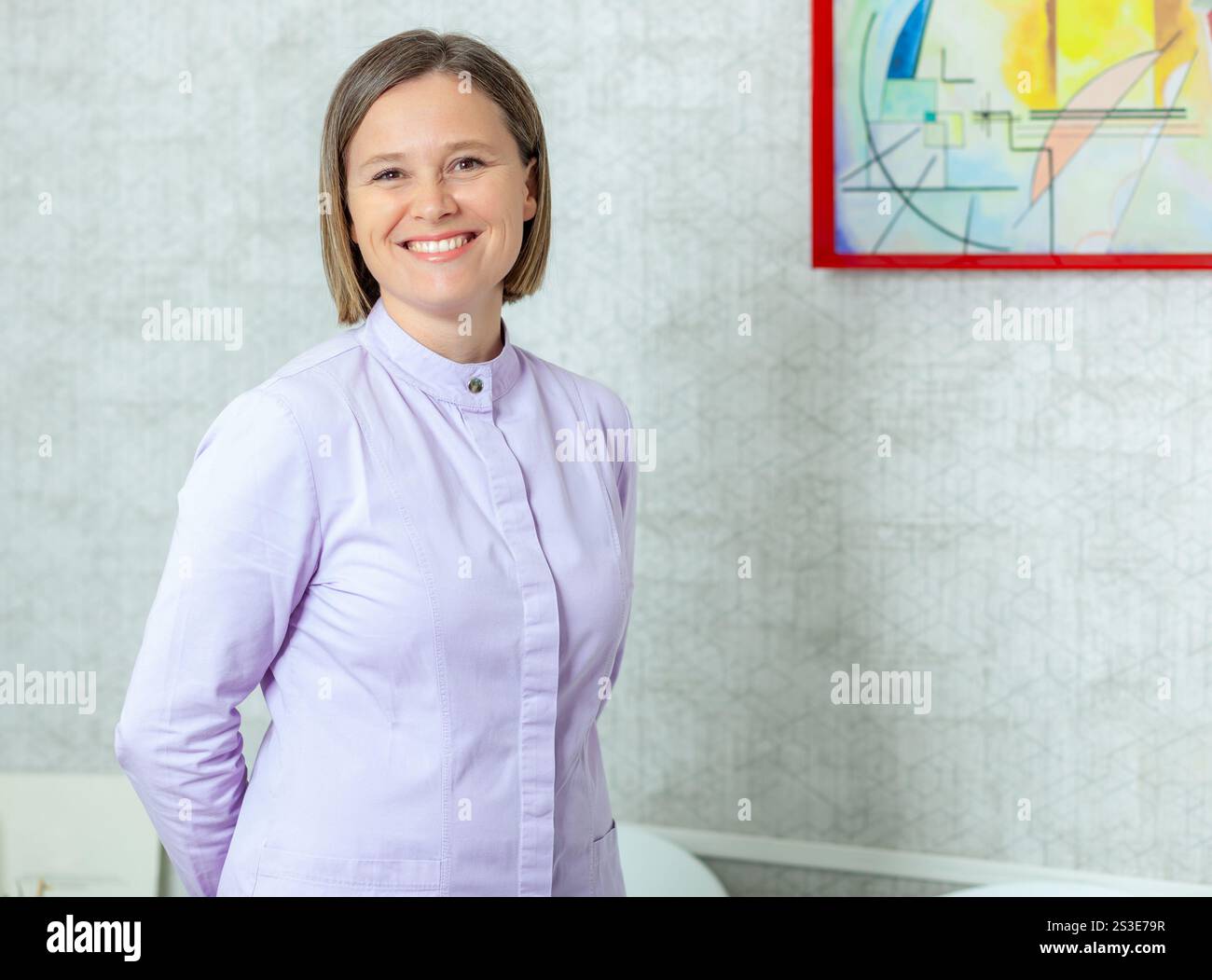 Dentiste professionnelle souriante posant avec confiance dans son cabinet moderne, mettant en valeur son expertise en soins dentaires et en service aux patients Banque D'Images