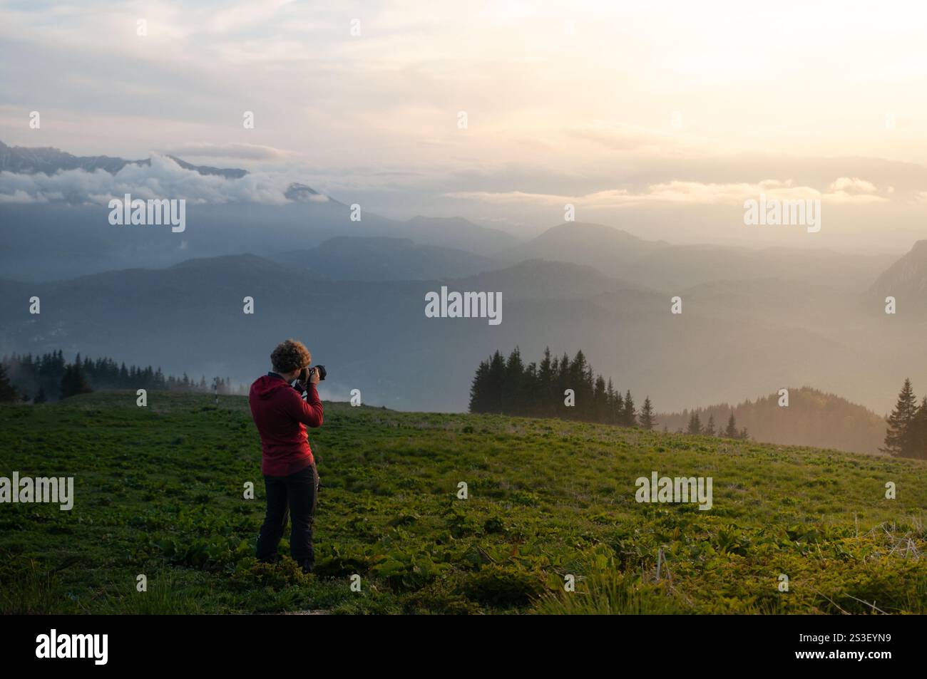 Silhouette d'un photographe au lever du soleil dans les montagnes, capturant la lumière dorée et la beauté brumeuse dans une scène extérieure sereine et inspirante. Banque D'Images