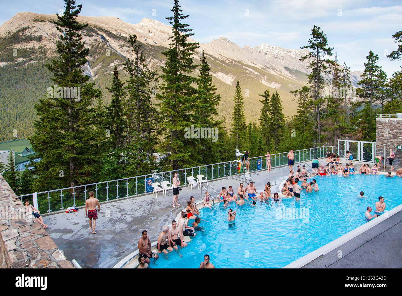 BANFF, CANADA - 2 JUILLET 2014 : les visiteurs d'été se baignent dans l'eau chaude et riche en minéraux des sources thermales supérieures de Banff avec Rundle et Cascade Mountains Banque D'Images