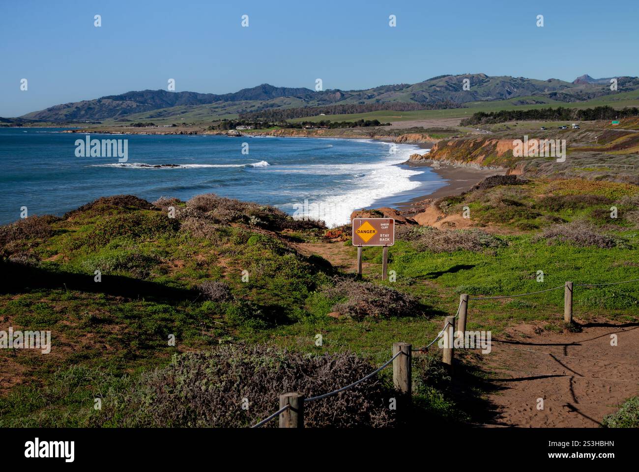 Une belle vue sur la côte à Cambria, CA présente des falaises ondulantes et des eaux turquoises sous un ciel bleu clair. Un sentier de randonnée mène à la plage, inviti Banque D'Images